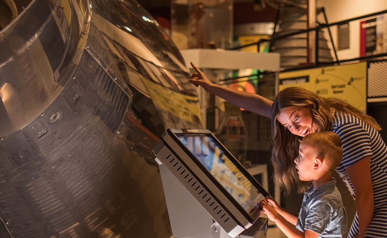 Mom and son looking at a space capsule at Armstrong Air & Space Museum