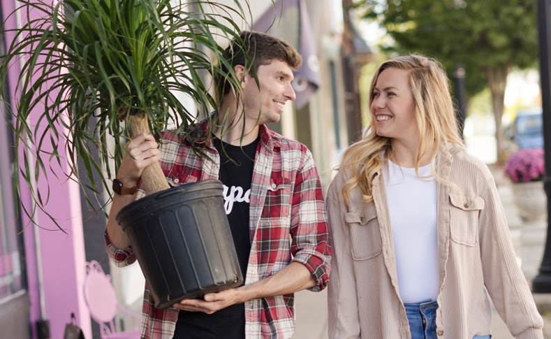 Couple holding a houseplant on the sidewalk while shopping in Downtown Wapakoneta Ohio